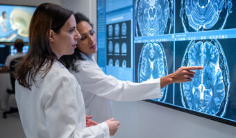 Female doctor pointing out symptom on MRI scan to her colleague.