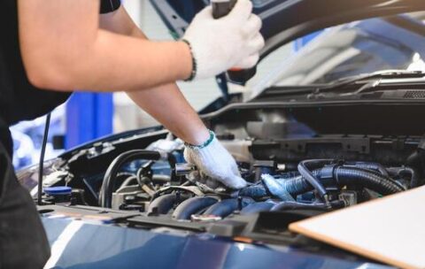 male-mechanic-holds-flashlight-to-examine-car