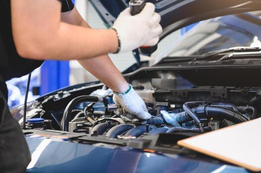 male-mechanic-holds-flashlight-to-examine-car