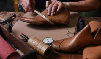 Shoemaker measuring a shoe with measure tape in workshop